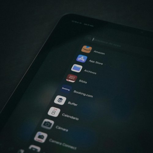Dark themed close-up of a tablet screen displaying various applications in a vertical shot.